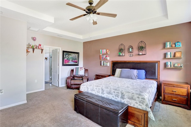 carpeted bedroom featuring a tray ceiling, connected bathroom, and ceiling fan