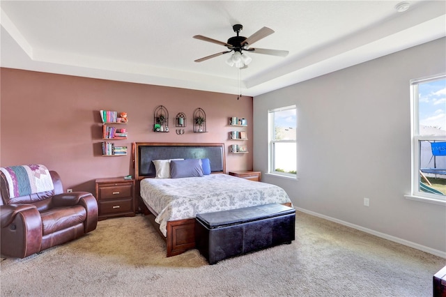 carpeted bedroom featuring a raised ceiling and ceiling fan