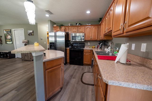 kitchen with appliances with stainless steel finishes, sink, decorative light fixtures, dark hardwood / wood-style floors, and a kitchen island