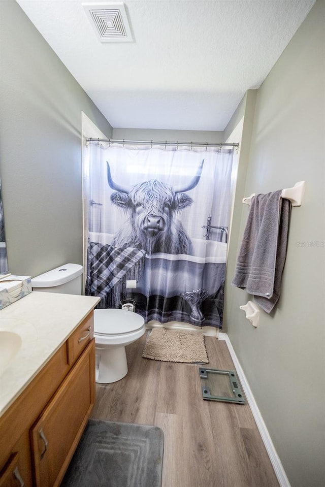 bathroom featuring a textured ceiling, vanity, hardwood / wood-style flooring, and toilet