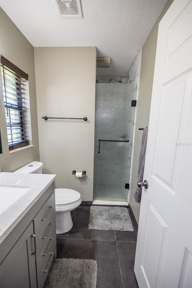 bathroom featuring a shower with door, vanity, a textured ceiling, and tile patterned flooring