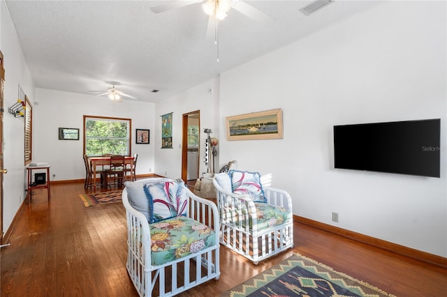 living room with a textured ceiling, ceiling fan, and dark hardwood / wood-style floors