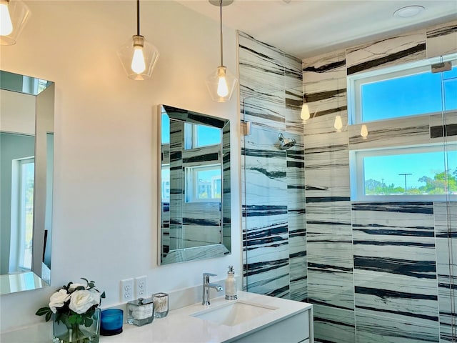 bathroom featuring tiled shower, vanity, and plenty of natural light