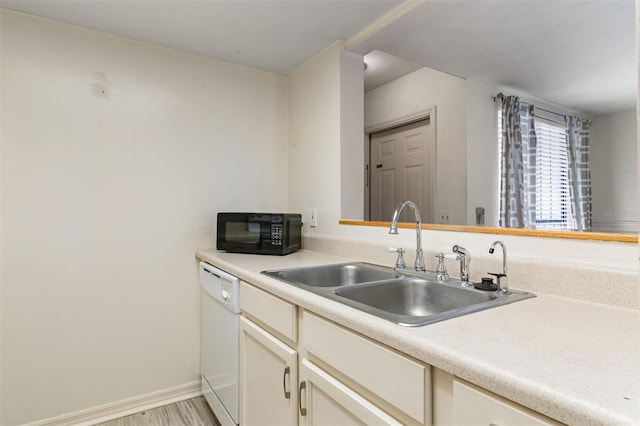 kitchen featuring light hardwood / wood-style floors, dishwasher, sink, and cream cabinetry