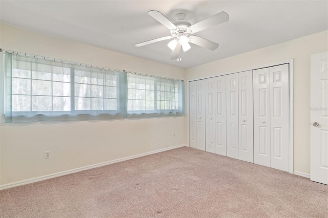 unfurnished bedroom with light colored carpet, ceiling fan, and a closet