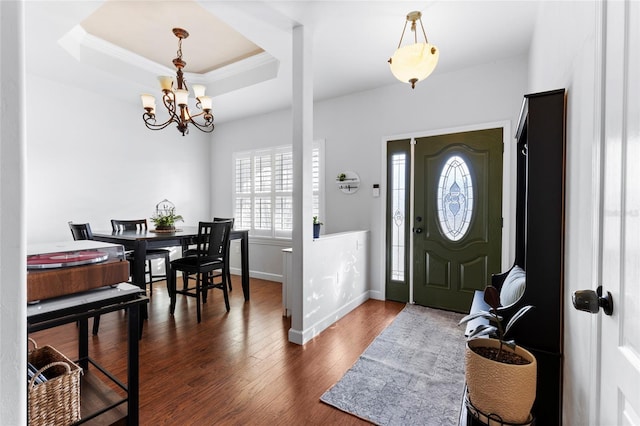 entrance foyer featuring a tray ceiling, dark wood-type flooring, and a notable chandelier