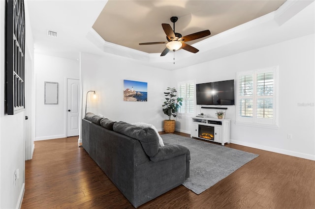 living room featuring ceiling fan, dark hardwood / wood-style flooring, and a tray ceiling