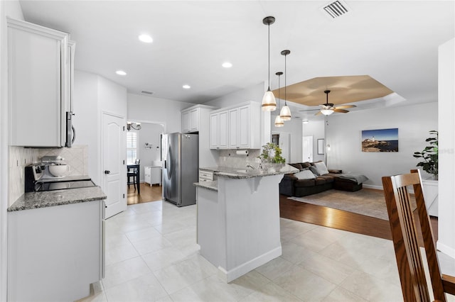 kitchen with stainless steel fridge, stove, tasteful backsplash, ceiling fan, and white cabinetry