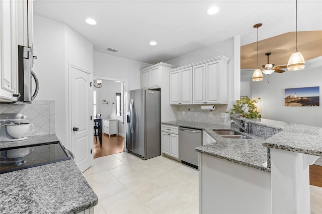 kitchen featuring white cabinets, sink, decorative light fixtures, kitchen peninsula, and stainless steel appliances