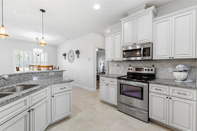 kitchen with white cabinetry, sink, stainless steel appliances, decorative light fixtures, and decorative backsplash