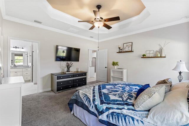 bedroom featuring ensuite bath, ceiling fan, a raised ceiling, light carpet, and ornamental molding