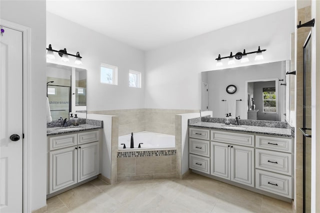 bathroom with vanity, a relaxing tiled tub, and tile patterned floors