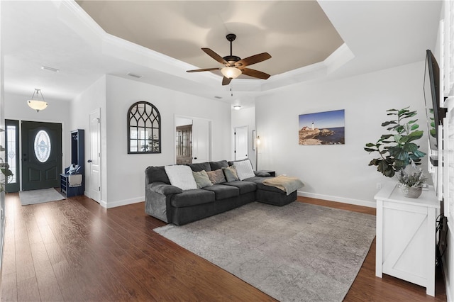 living room with ceiling fan, a raised ceiling, and dark wood-type flooring