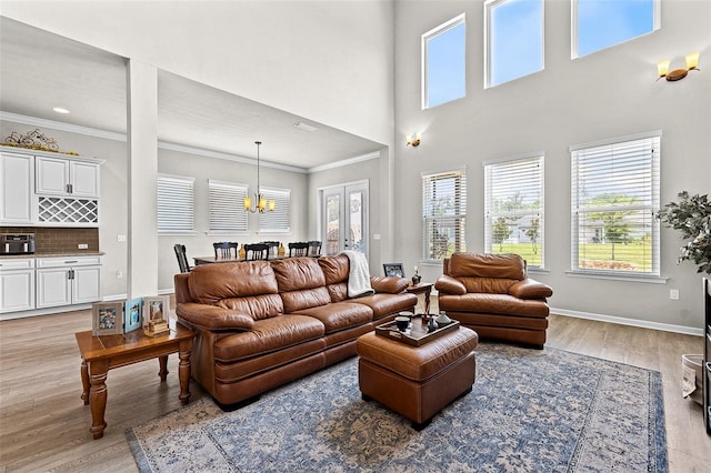 living room featuring light hardwood / wood-style floors, an inviting chandelier, and crown molding