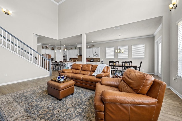 living room featuring an inviting chandelier, wood-type flooring, a high ceiling, and ornamental molding