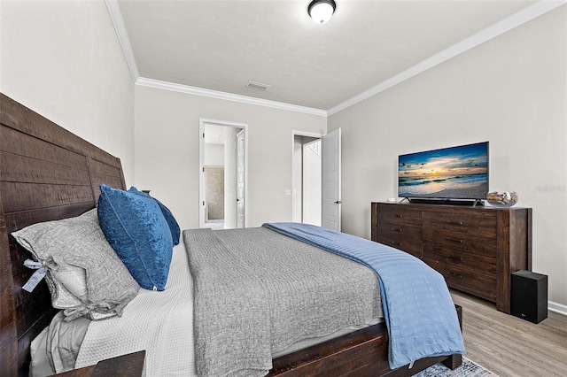 bedroom featuring hardwood / wood-style flooring, crown molding, and connected bathroom