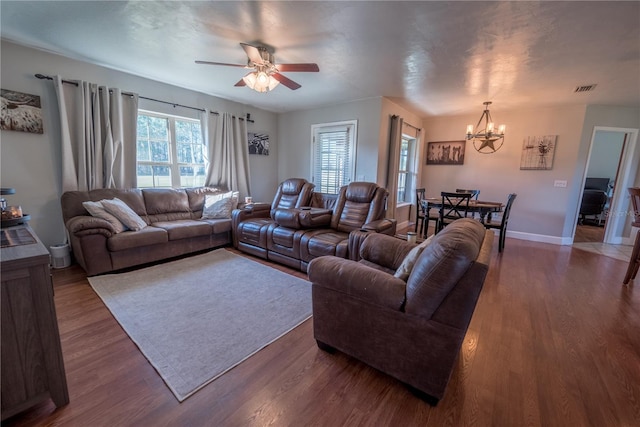 living room with ceiling fan with notable chandelier and dark wood-type flooring