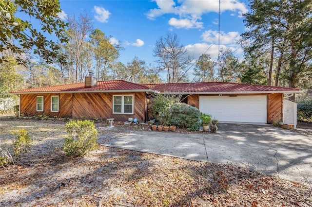 ranch-style house featuring an attached garage, a tile roof, a chimney, and concrete driveway