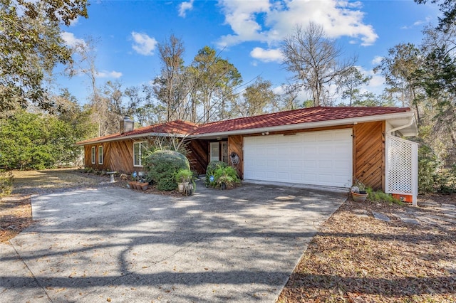 view of front of home with an attached garage, a chimney, and concrete driveway