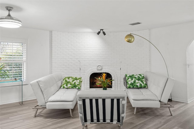 living area featuring baseboards, a fireplace, visible vents, and wood finished floors