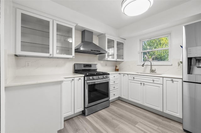 kitchen featuring stainless steel appliances, wall chimney exhaust hood, light countertops, and glass insert cabinets