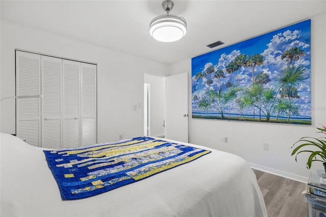 bedroom featuring a closet, wood finished floors, visible vents, and baseboards