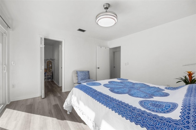 bedroom with wood finished floors, visible vents, and baseboards