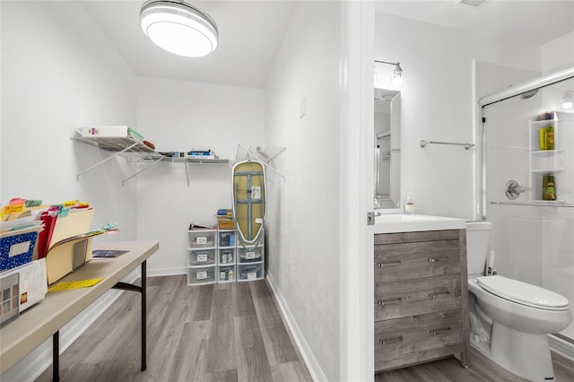 bathroom featuring baseboards, toilet, wood finished floors, vanity, and a shower stall