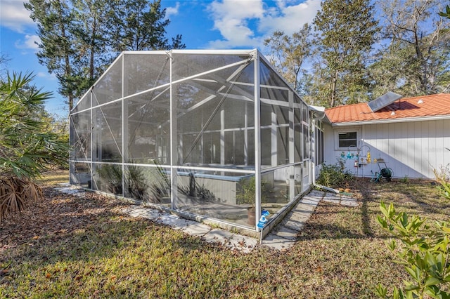 exterior space featuring a tile roof and glass enclosure