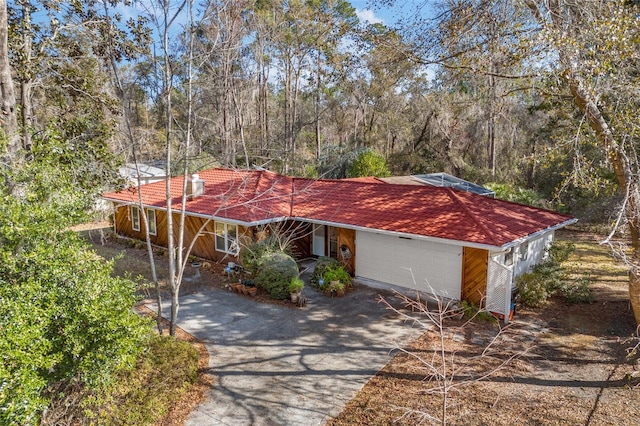 view of front of property featuring a garage, driveway, and a tiled roof