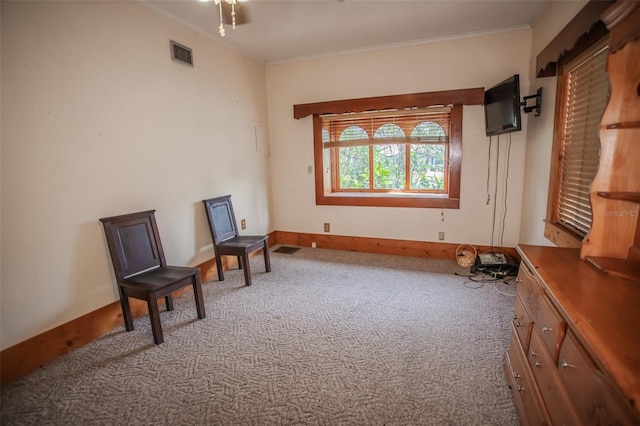 living area with crown molding, ceiling fan, and light colored carpet