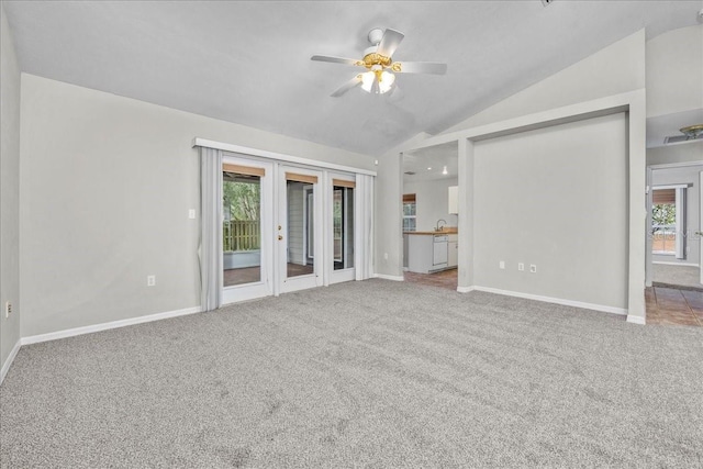 unfurnished living room with ceiling fan, french doors, sink, carpet floors, and vaulted ceiling