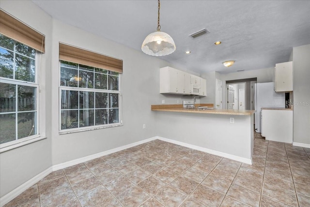 kitchen with white cabinets, plenty of natural light, kitchen peninsula, and hanging light fixtures