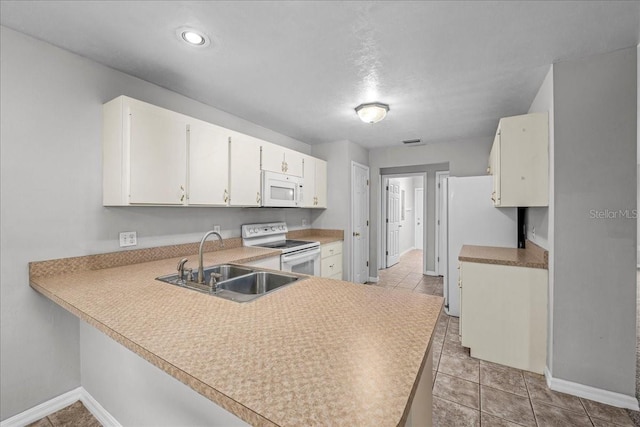 kitchen featuring sink, light tile patterned floors, kitchen peninsula, white appliances, and white cabinets