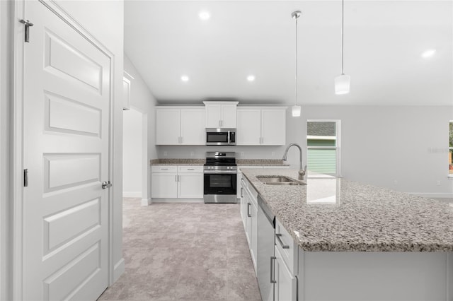 kitchen with stainless steel appliances, a kitchen island with sink, sink, pendant lighting, and white cabinetry