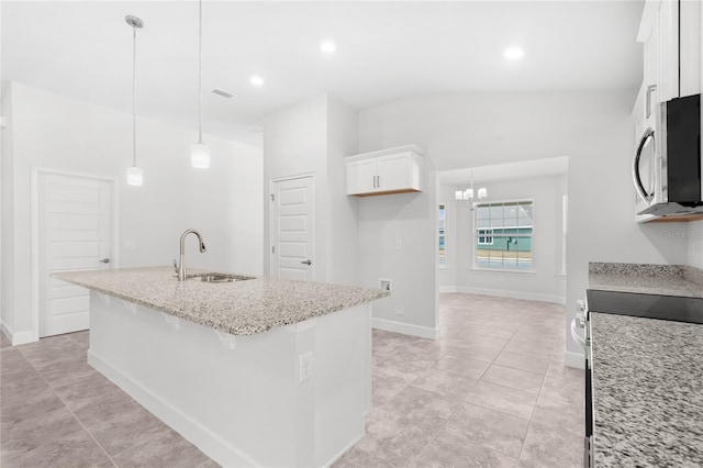 kitchen with light stone counters, sink, decorative light fixtures, a center island with sink, and white cabinets