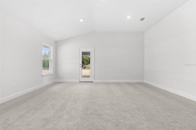 spare room with light colored carpet and vaulted ceiling