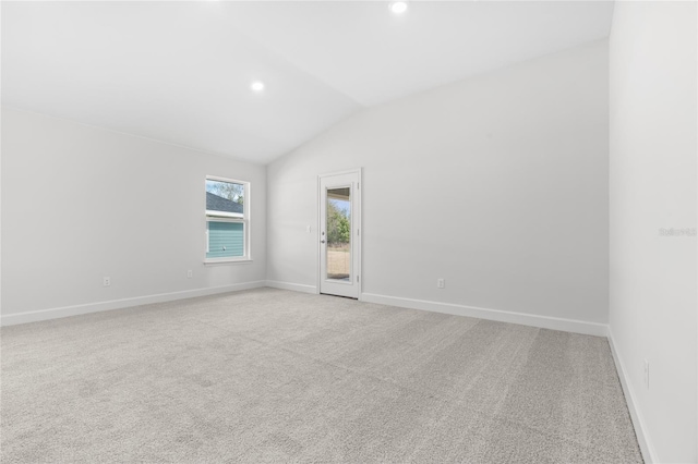 carpeted spare room featuring vaulted ceiling