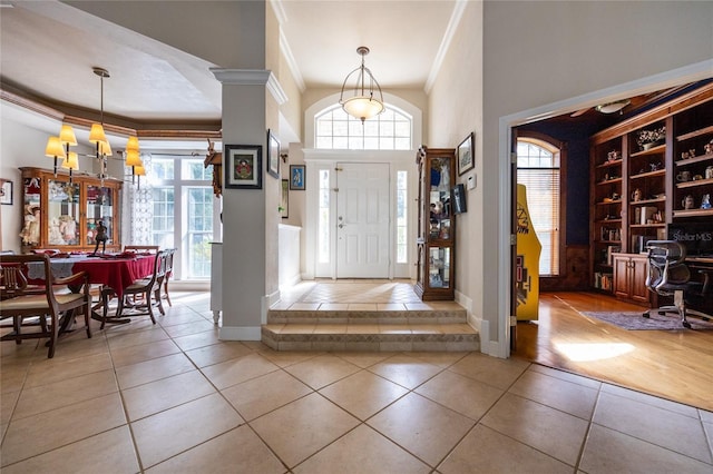 foyer entrance with light tile patterned flooring, crown molding, and a chandelier