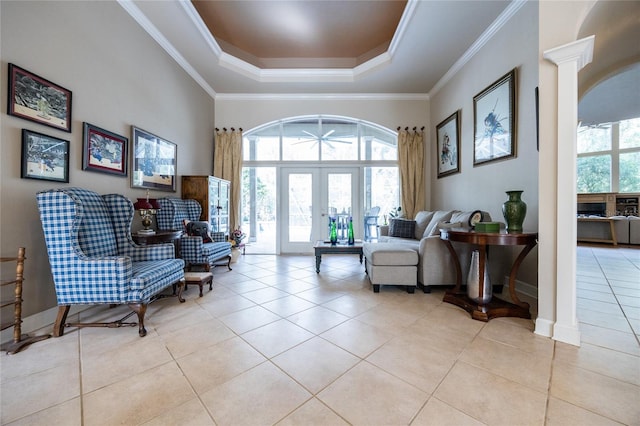 living area featuring ornate columns, french doors, a raised ceiling, light tile patterned flooring, and ornamental molding