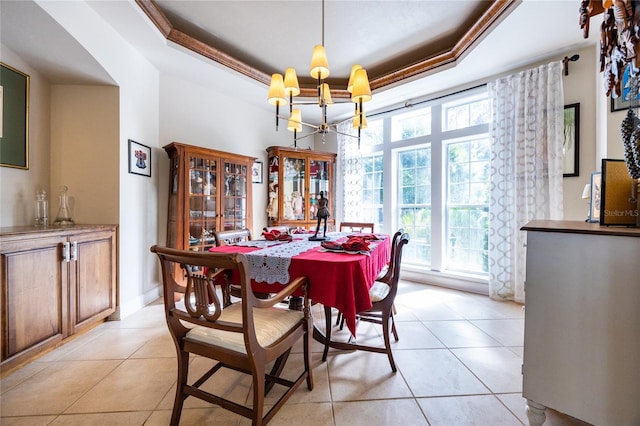 tiled dining room featuring a raised ceiling, crown molding, and a chandelier