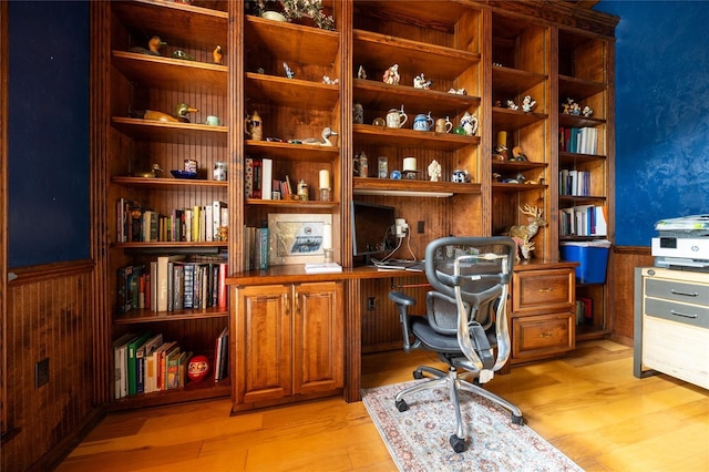 office with wood walls and light hardwood / wood-style flooring