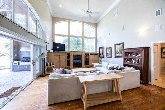 living room with hardwood / wood-style flooring, ornamental molding, and a high ceiling