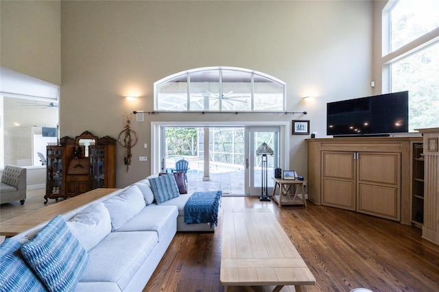 living room with ceiling fan, a towering ceiling, and dark wood-type flooring