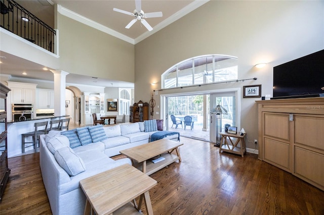 living room with ceiling fan, dark hardwood / wood-style floors, ornamental molding, and a high ceiling