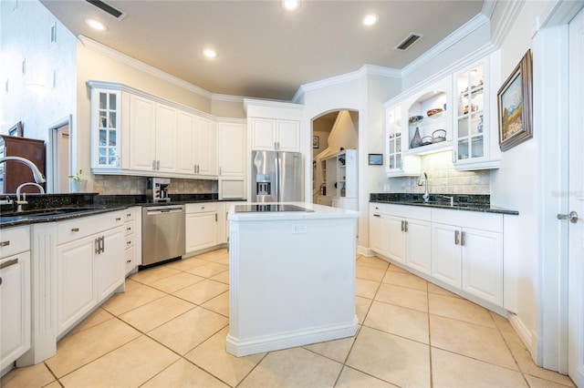 kitchen with dark stone counters, white cabinets, sink, appliances with stainless steel finishes, and a kitchen island