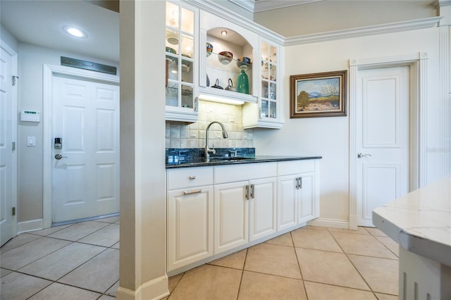 bar featuring white cabinetry, sink, backsplash, dark stone counters, and light tile patterned flooring