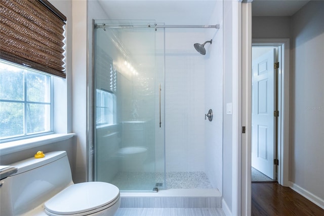 bathroom featuring hardwood / wood-style flooring, an enclosed shower, and toilet