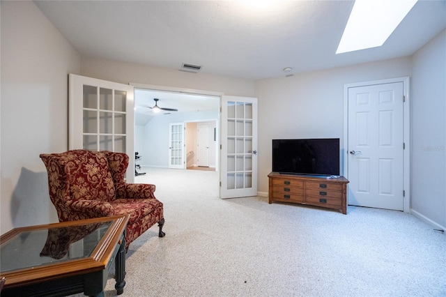 sitting room featuring a skylight, light carpet, french doors, and ceiling fan