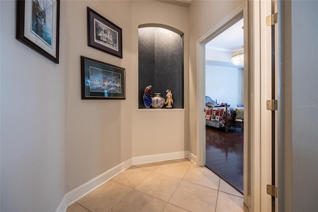 corridor featuring light tile patterned floors and ornamental molding